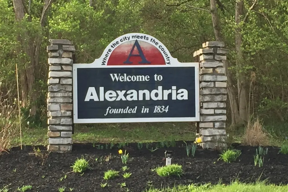 Welcome sign for Alexandria with stone pillars, stating founded in 1834 and a red A emblem above the text.