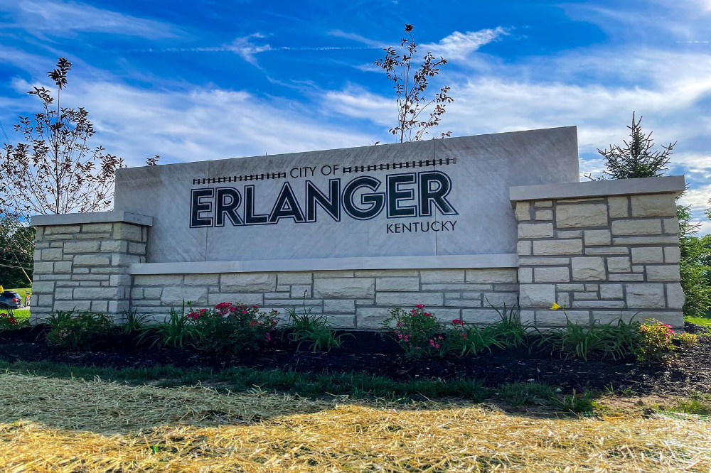 Stone monument sign that reads 'City of Erlanger Kentucky' with a landscaped flower bed in front