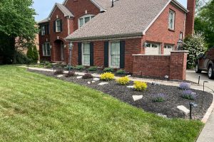 Brick two-story house with landscaped front yard, curved walkway, and a driveway with a parked SUV.