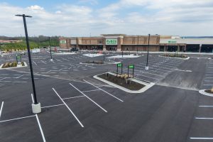 Wide view of a nearly empty shopping center parking lot with a Publix store in the background.